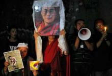 Tibetanos exiliados con un retrato del Dalai Lama y una imagen de un joven que se inmoló (izq), el 30 de septiembre. (AFP)